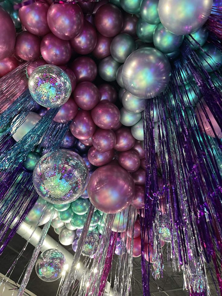 the ceiling is covered with shiny balls and streamers in purple, blue, and green colors