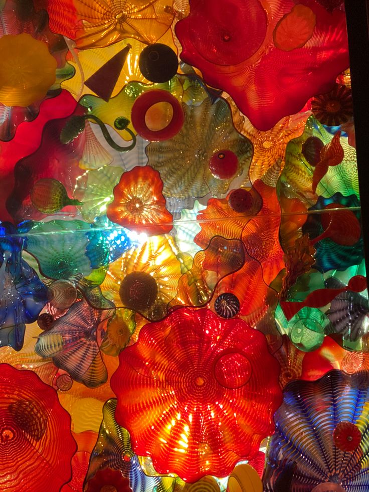 many colorful glass flowers are hanging from the ceiling