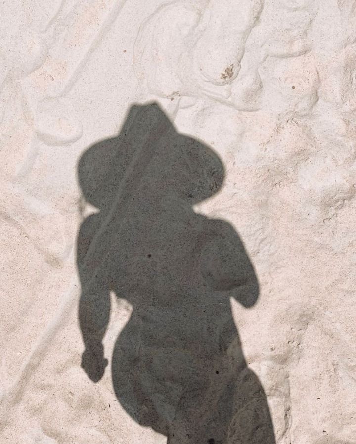 the shadow of a person standing in the sand