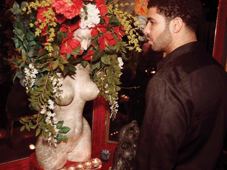 a man standing next to a statue covered in flowers