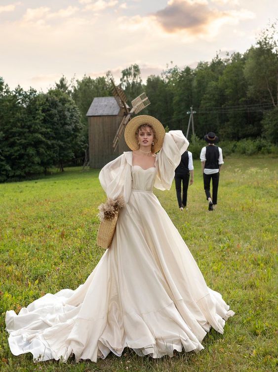 a woman in a white dress and hat walking across a field