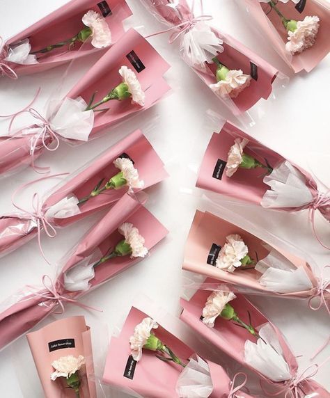 pink and white flowers are wrapped in clear cellophane bags with ribbon tied around them