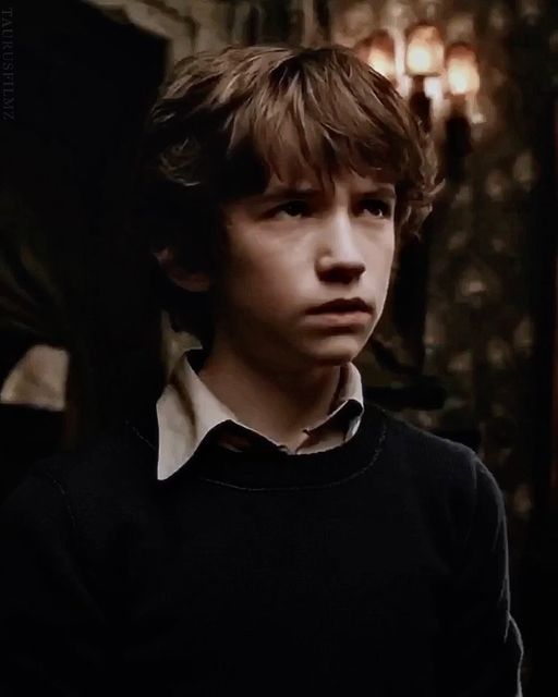 a young boy in a black sweater looking at the camera with an intense look on his face