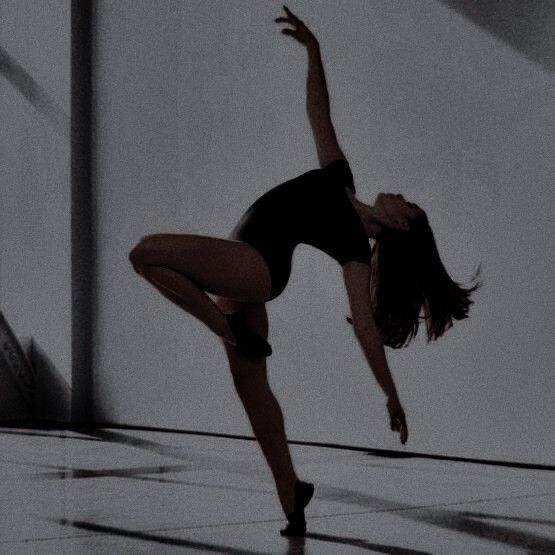 a woman is doing a dance move in the middle of an empty room with white walls