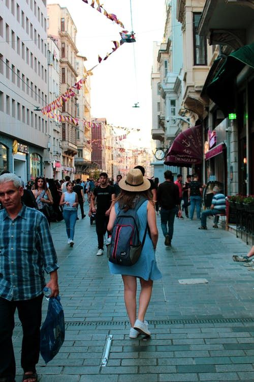 people are walking down the street with backpacks on their backs and one person is carrying a bag