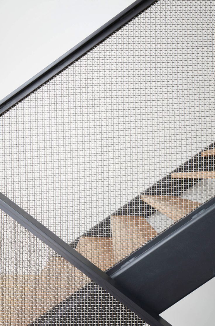 a close up view of a stair case with metal mesh covering the railing and handrails