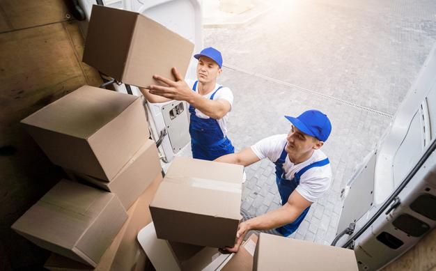 two men in blue hats are moving boxes