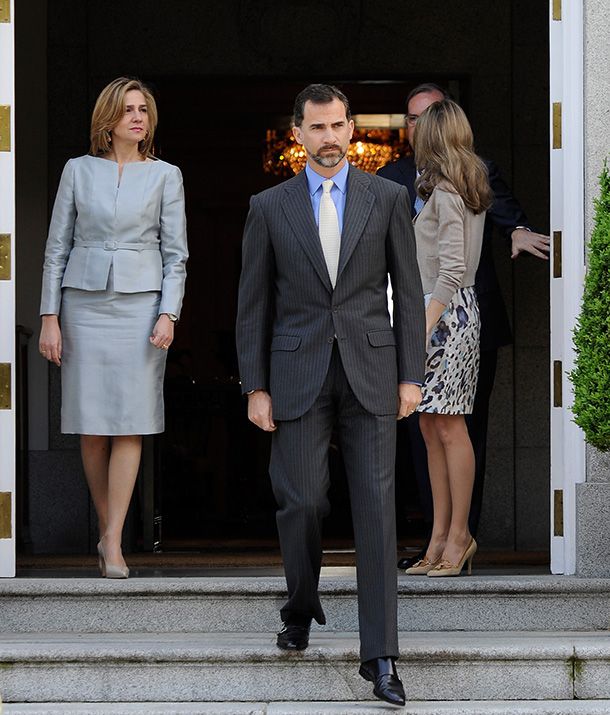 a man in a suit and tie walking out of a doorway with two women standing behind him