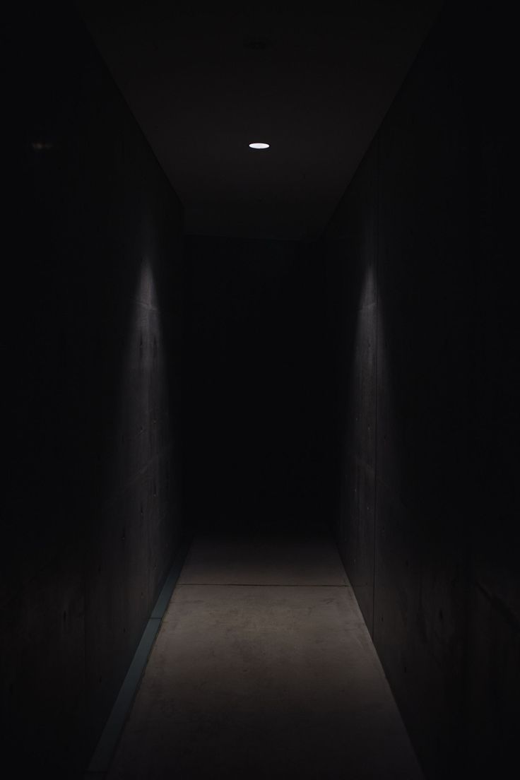 an empty dark hallway with light at the end