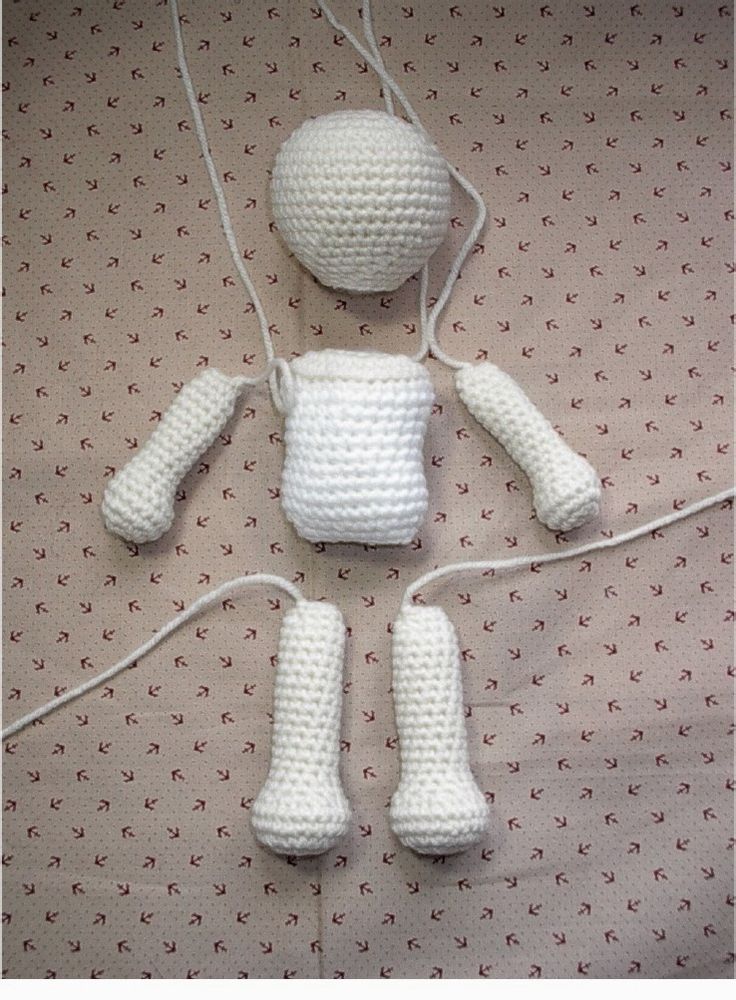 a crocheted doll is laying on a bed with white socks and booties