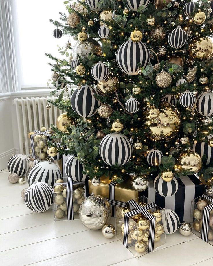 a christmas tree decorated with black and white striped baubs, ornaments and presents