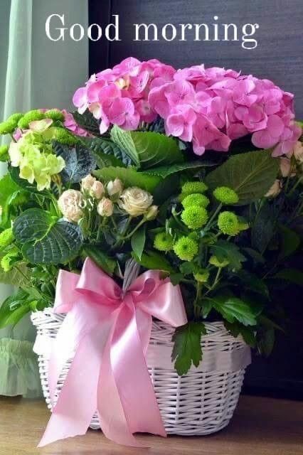 a white basket filled with pink and green flowers