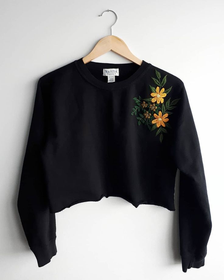 a black crop top with yellow flowers on the front and green leaves on the back