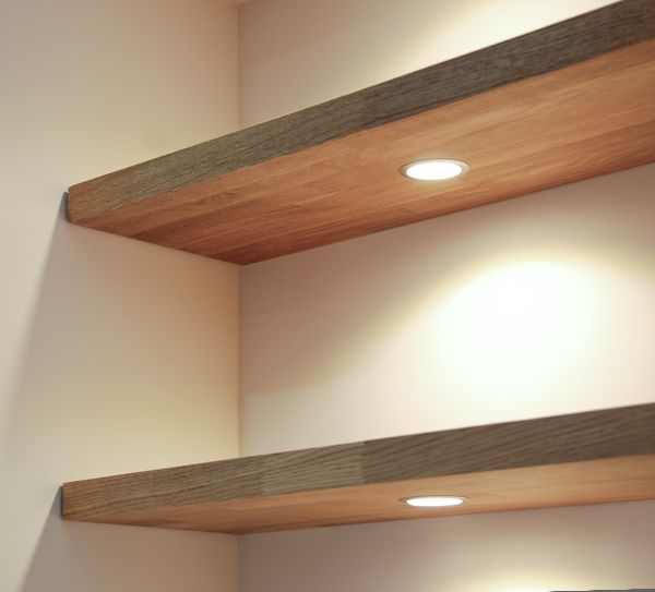 two wooden shelves with lights above them