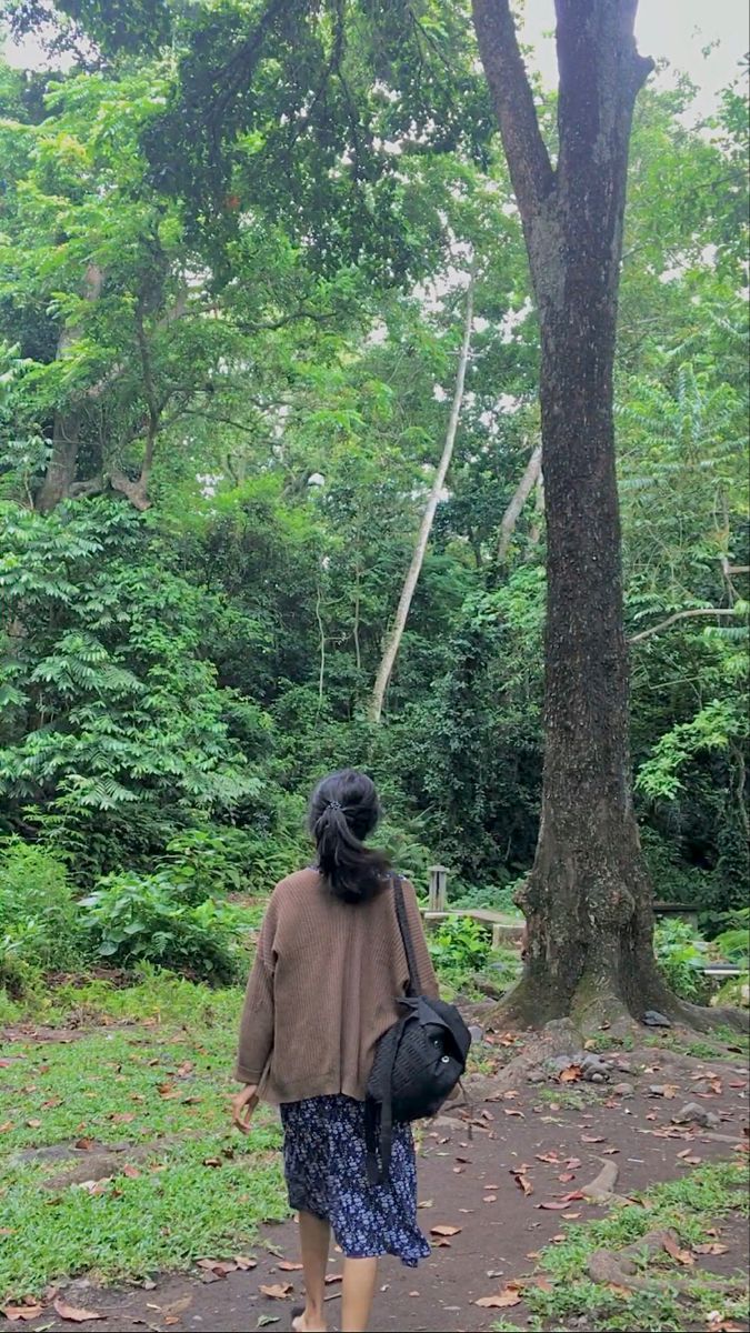 a woman walking down a path in the woods