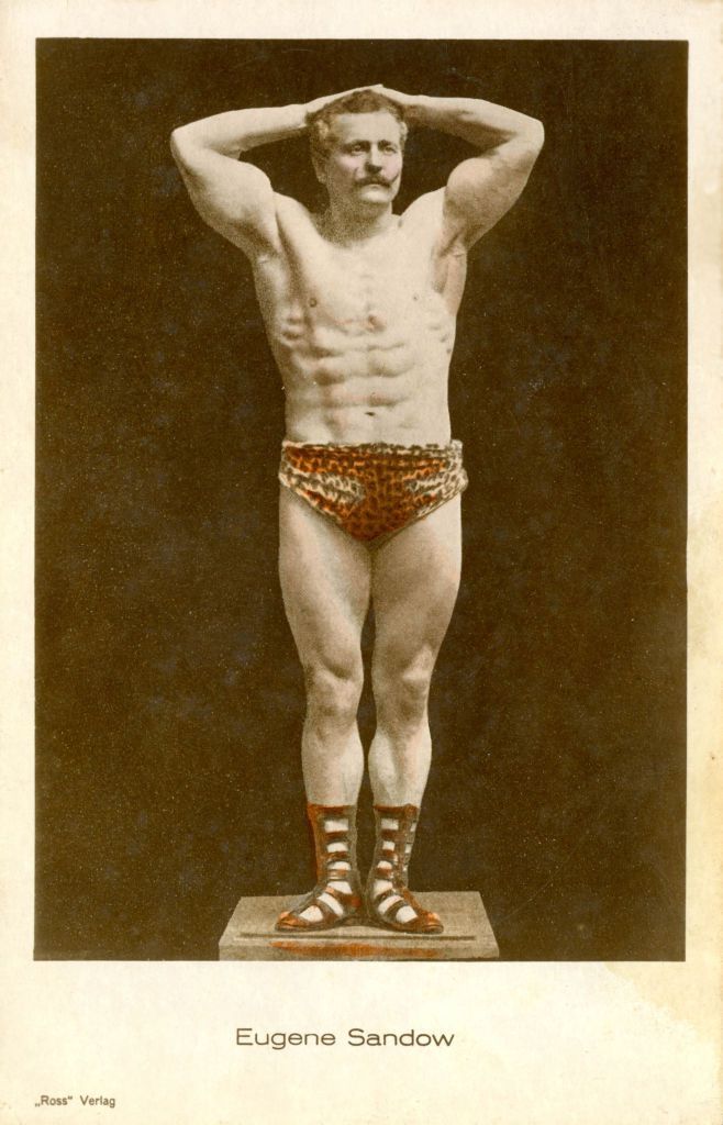 an old photo of a man with his hands on his head and wearing leopard print trunks