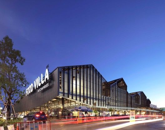 an image of a building that is lit up at night with cars passing by it