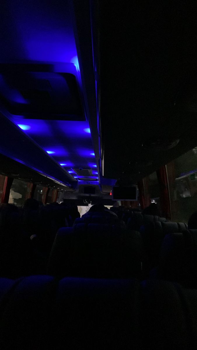 the interior of an empty bus with blue lights on it's ceiling and seats