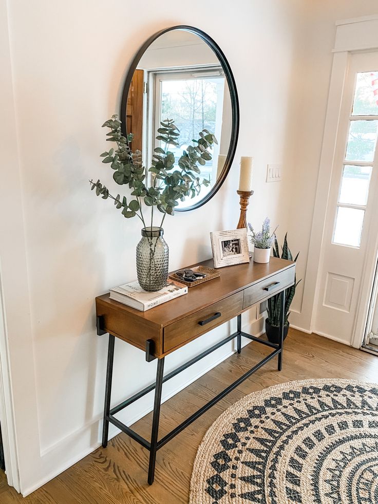 a wooden table with a mirror on top of it next to a rug and door