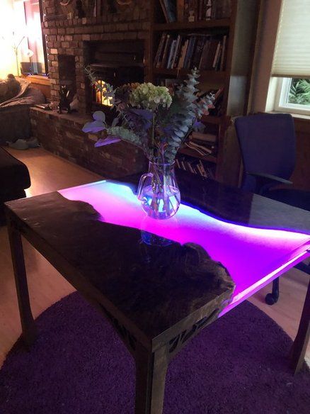 a glass vase with flowers on a table in front of a fire place and bookshelf