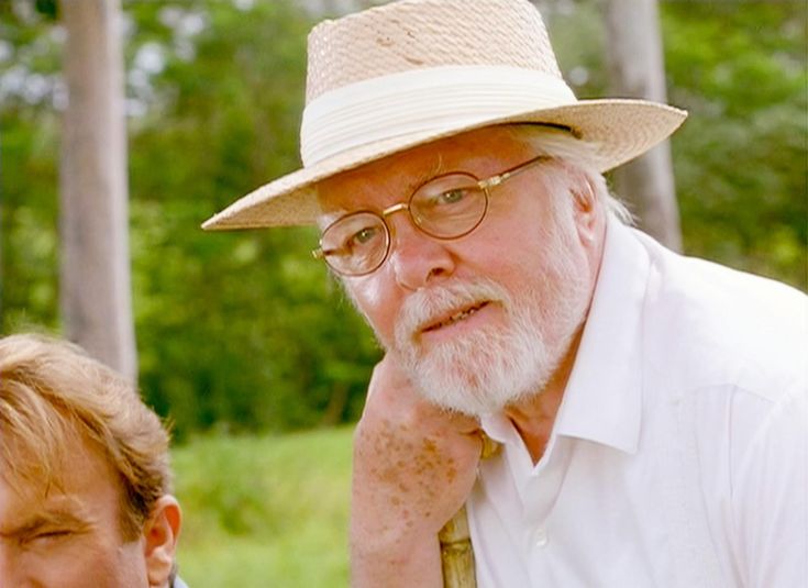 an older man with glasses and a hat is standing next to a younger man in a white shirt