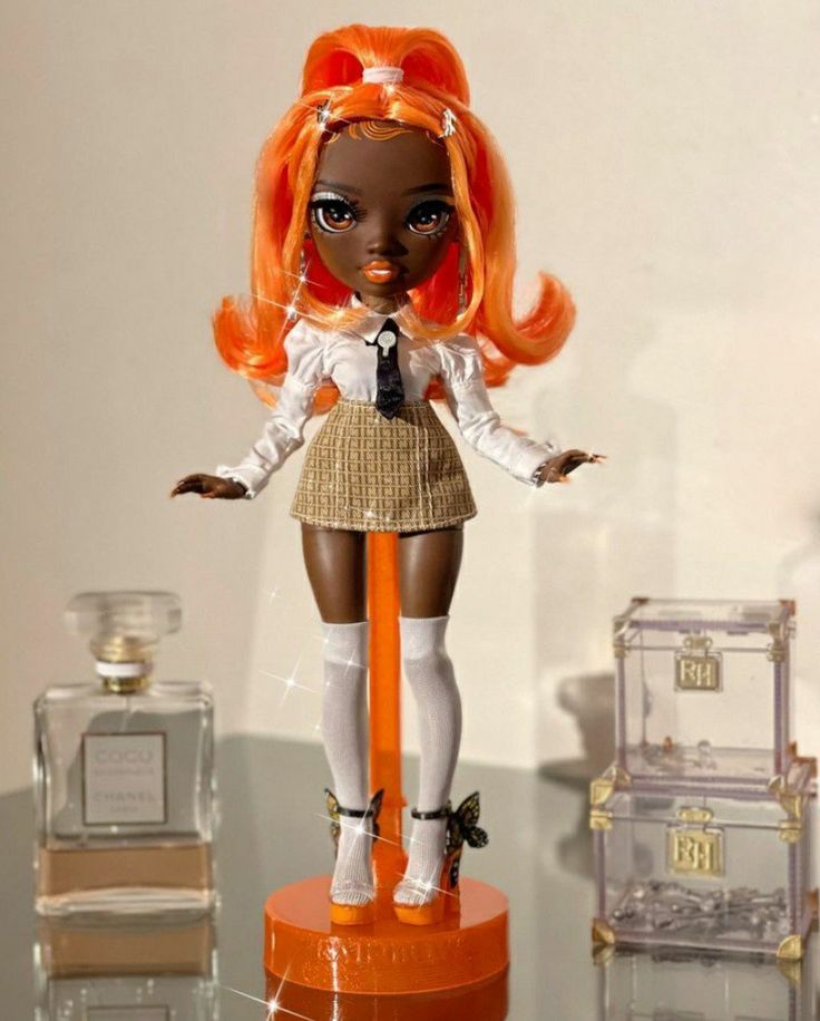 a doll with orange hair is standing on an orange stand next to some perfume bottles