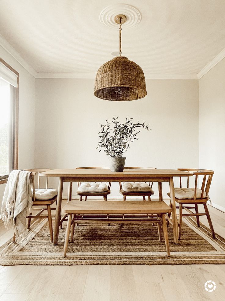 a dining room table with chairs and a bench in front of a large window on the wall