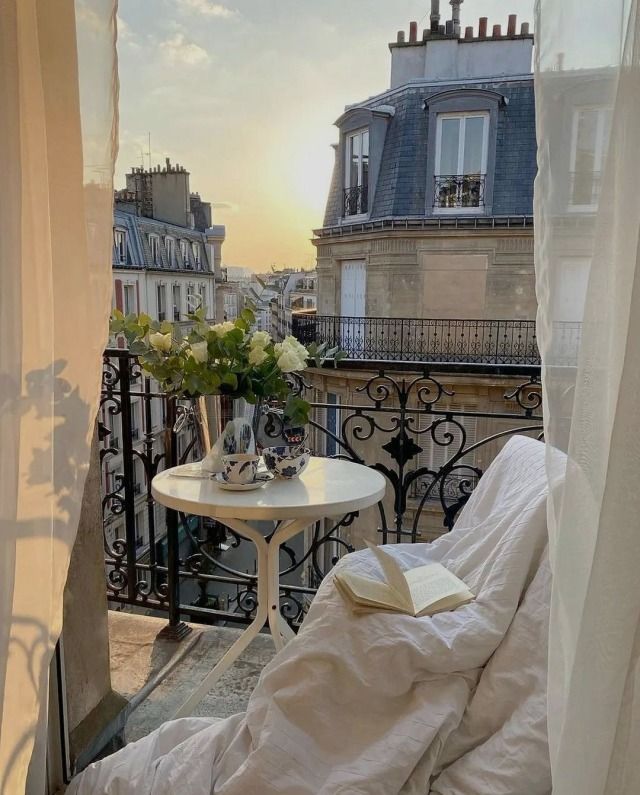 a balcony with a table and chairs on it, overlooking the cityscape at sunset