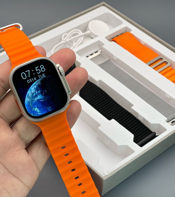 a person holding an apple watch in their hand with the case open and orange straps