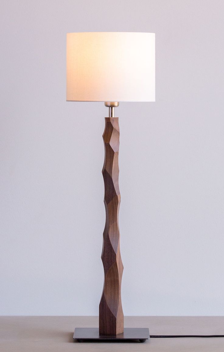 a wooden lamp with a white shade on it's side and a black base