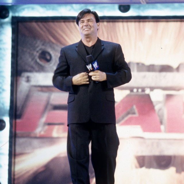a man standing in front of a large screen with his hands clasped to his chest