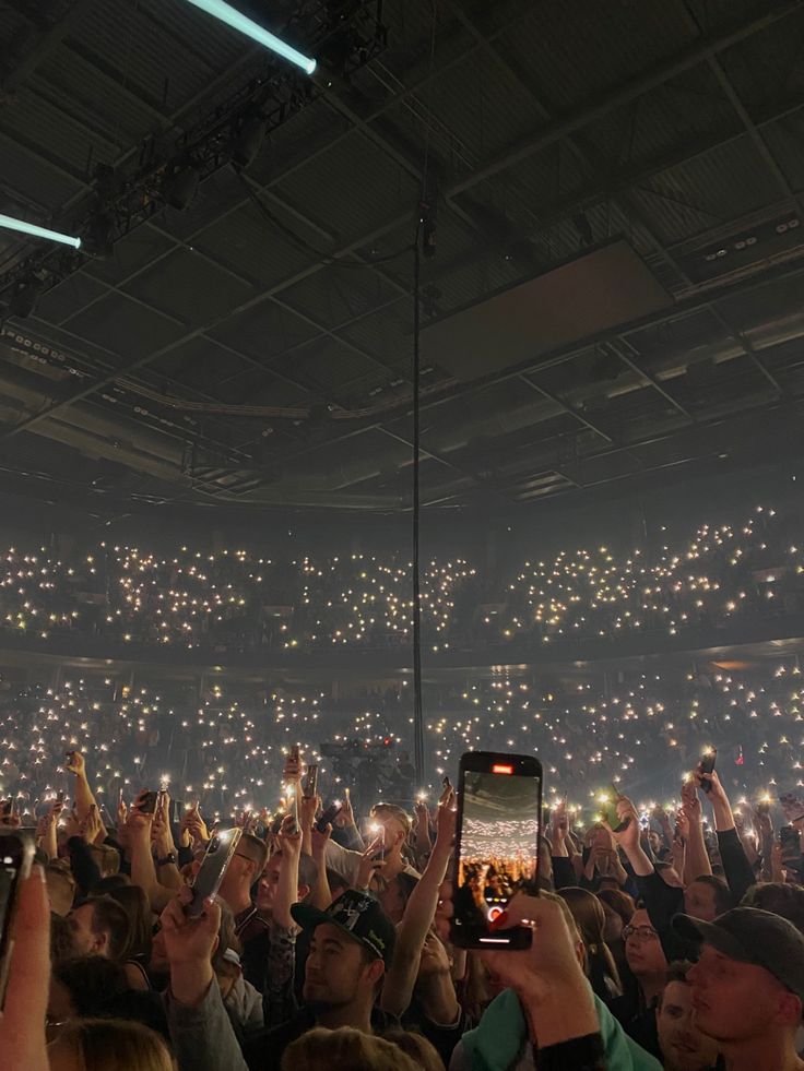 a large group of people holding up their cell phones in the air at a concert