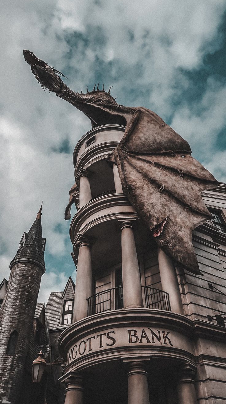 a giant dragon statue on top of a building next to a tall tower with a sign that says not's bank