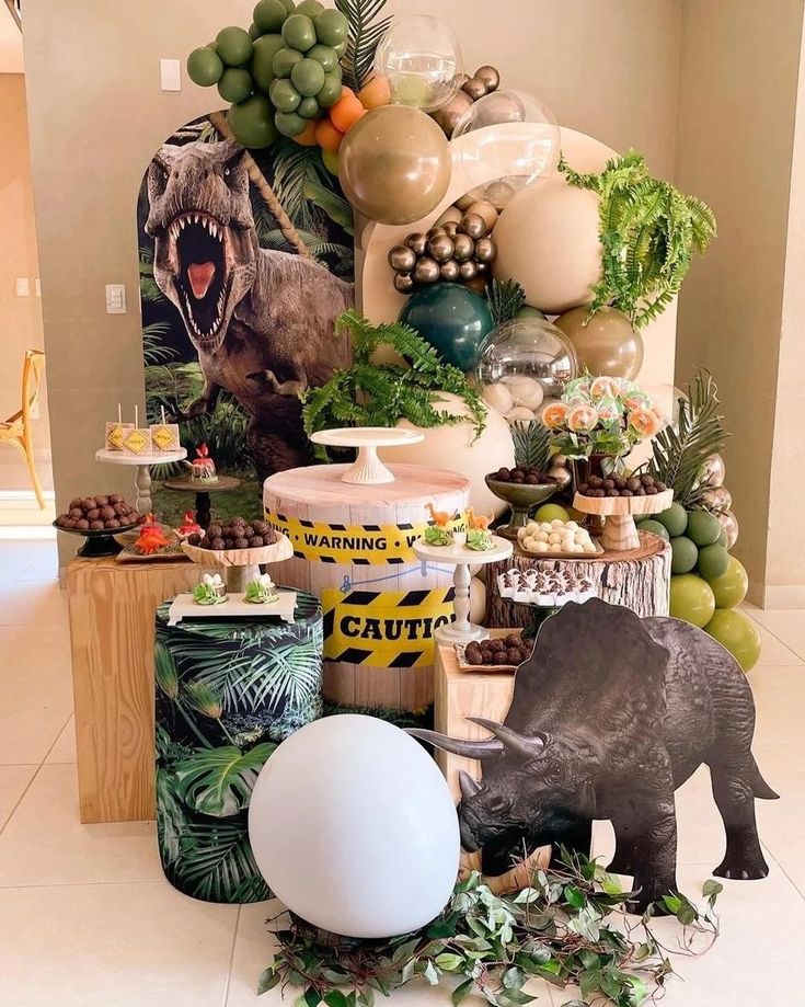 an animal themed birthday party with balloons and jungle decorations on the wall, including dinosaur figurines