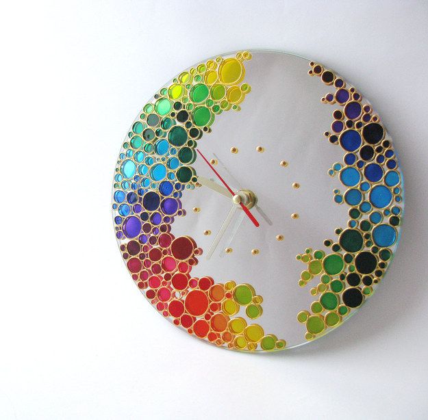 a clock made out of colored circles on a white surface with gold dots around it