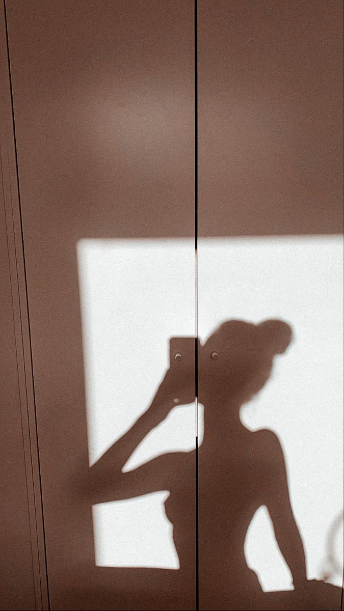 the shadow of a woman standing in front of a door with her hand on her head