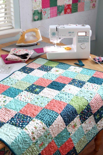 a sewing machine sitting on top of a wooden table next to a quilted blanket