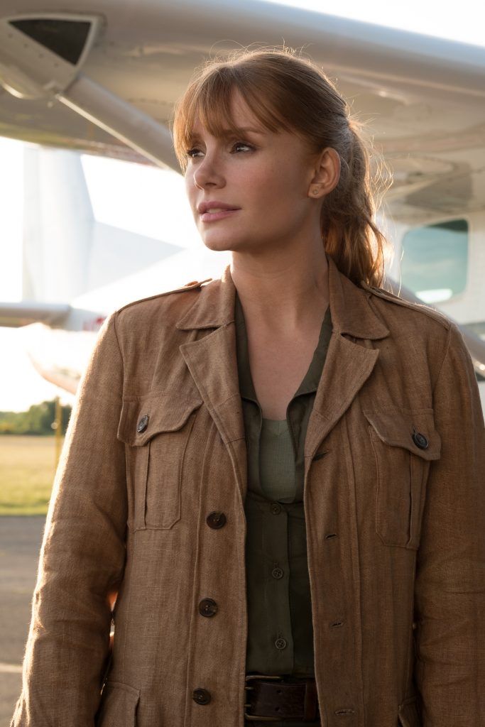 a woman standing in front of an airplane looking off into the distance with her hand on her hip