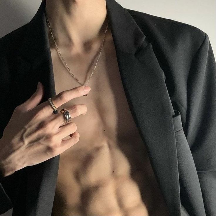 a shirtless man wearing a ring and jacket