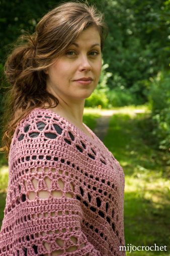 a woman wearing a pink crocheted shawl in the woods