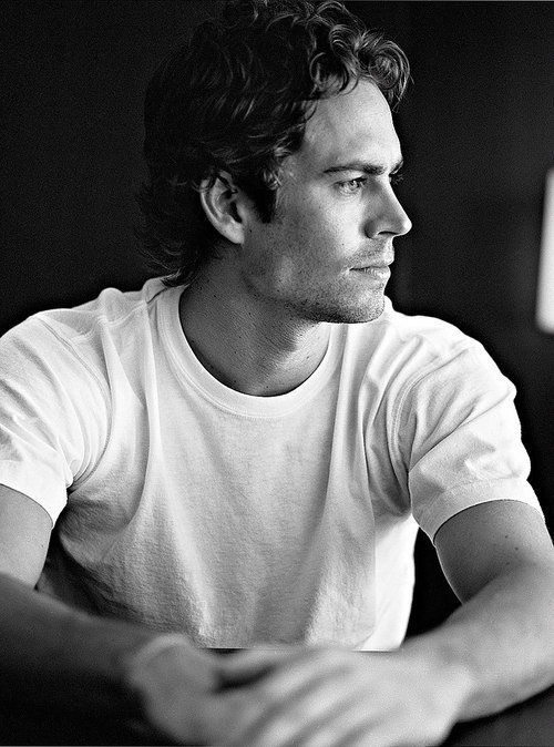 a black and white photo of a man sitting at a table looking off into the distance