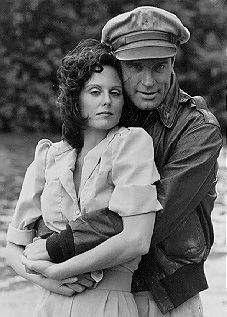 black and white photograph of a man hugging a woman in front of a body of water