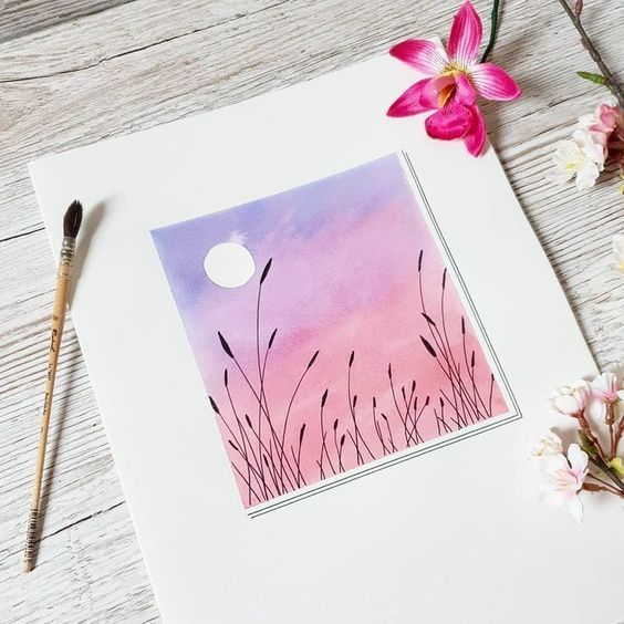 a card with pink and purple watercolors on it next to flowers, paintbrushes and an acrylic pen