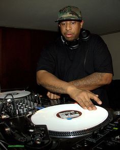 a man with headphones on and dj mixing in front of his turntables