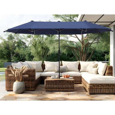 an outdoor living area with wicker furniture and blue umbrella over the sectional couches