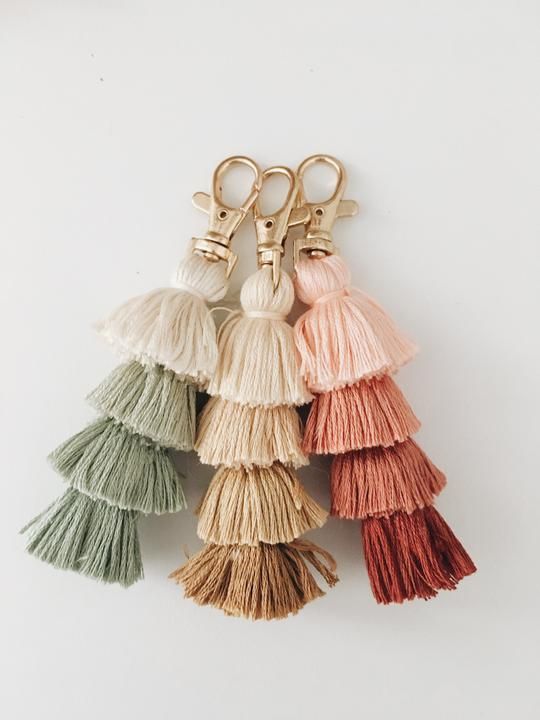 five tasseled keychains with gold tone metal handles on each side, all in different colors