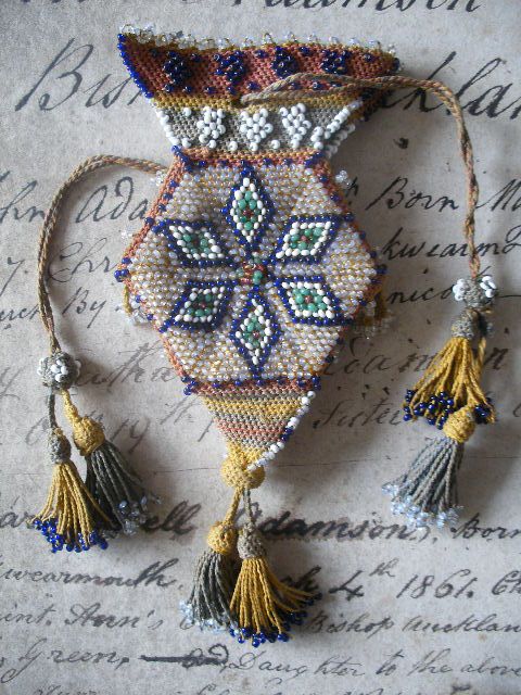 an old fashioned beaded purse with tassels and beads on it's side