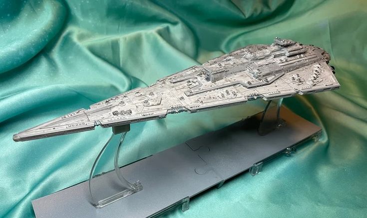 a model of a star wars ship is on display in front of a green cloth