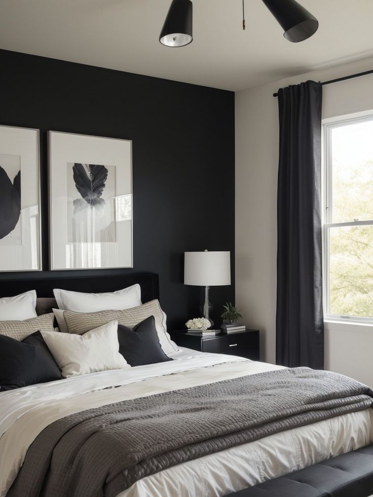 a bedroom with black walls and white bedding, two framed pictures on the wall