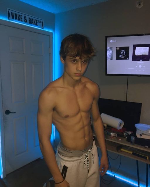a shirtless young man standing in front of a tv with his hands on his hips